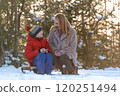 Portrait of young woman and child boy during picnic in winter in forest. Mother and son drink hot tea from thermos. 120251494