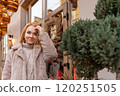 Blond young woman with beautiful eyes in a fur coat on a festive street. Christmas mood. Holiday weekend 120251505