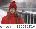 Portrait of a young girl in a red jacket on a background of winter landscape 120251510