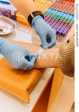 Healthcare professional applying a bandage after a blood draw procedure in a clinical setting Healthcare professional applying a bandage after a blood draw procedure in a clinical setting 120251555