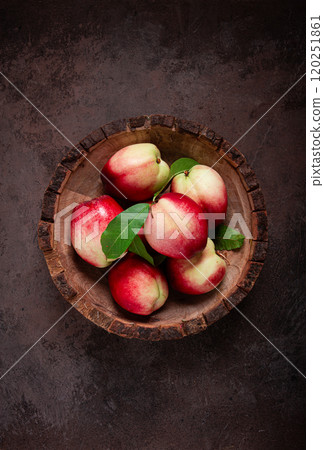 ripe nectarine, in a wooden plate, brown background, top view, no people, 120251861
