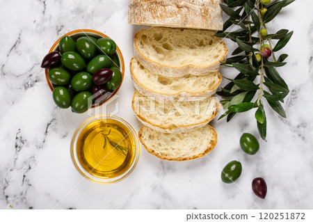 appetizer, sliced ciabatta bread, with olive oil, green olives, Chalkidiki olives, classic Green green olive, on a marble table, top view, no people, 120251872