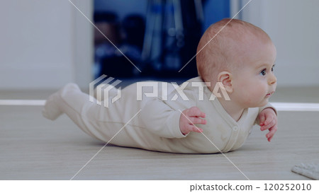 Innocent and playful, baby in a beige bodysuit lifting their head and gazing curiously. Baby crawling on the floor in a bright room Innocent and playful, baby in a beige bodysuit lifting their head and gazing curiously. Baby crawling on the floor in a bright room 120252010