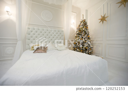 The interior of the New Year's bedroom. Room with a big white bed and a Christmas tree The interior of the New Year's bedroom. Room with a big white bed and a Christmas tree 120252153