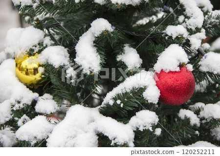 Fluffy branches of a Christmas tree in the snow decorated with Christmas decorations 120252211