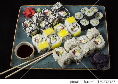 Seth sushi on a black background.Menu of the Japanese restaurant. Several sushi lined on a plate with bamboo sticks and soy sauce Seth sushi on a black background.Menu of the Japanese restaurant. Several sushi lined on a plate with bamboo sticks and soy sauce 120252327