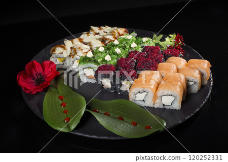 Seth sushi on a black background.Menu of the Japanese restaurant. Several sushi lined on a plate decorated with a decor of red berries, a flower and leaves Seth sushi on a black background.Menu of the Japanese restaurant. Several sushi lined on a plate decorated with a decor of red berries, a flower and leaves 120252331