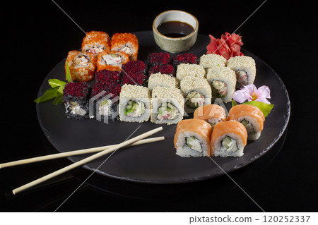 Seth sushi on a black background.Menu of the Japanese restaurant. Several sushi lined on a plate with bamboo sticks and soy sauce Seth sushi on a black background.Menu of the Japanese restaurant. Several sushi lined on a plate with bamboo sticks and soy sauce 120252337