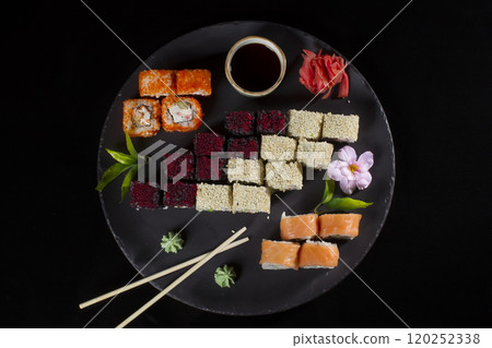 Seth sushi on a black background.Menu of the Japanese restaurant. Several sushi lined on a plate with bamboo sticks and soy sauce Seth sushi on a black background.Menu of the Japanese restaurant. Several sushi lined on a plate with bamboo sticks and soy sauce 120252338
