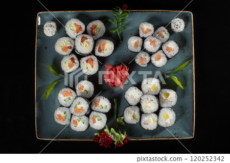 Seth sushi on a black background.Menu of the Japanese restaurant. Several sushi laid out on a plate with ginger sauce wasabi. Rolls from above 120252342