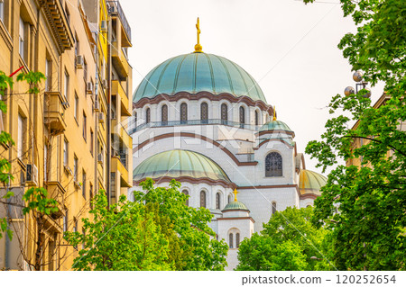 Saint Sava Cathedral stands majestically against a summer sky, surrounded by lush greenery and historical buildings. Visitors enjoy the vibrant atmosphere in Belgrade. Saint Sava Cathedral stands majestically against a summer sky, surrounded by lush greenery and historical buildings. Visitors enjoy the vibrant atmosphere in Belgrade. 120252654