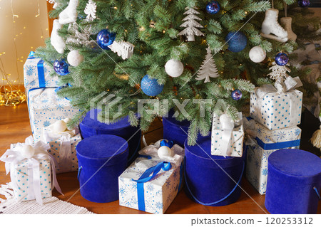 Beautiful Christmas tree decorated with festive ornaments and blue and white wrapped gift boxes Beautiful Christmas tree decorated with festive ornaments and blue and white wrapped gift boxes 120253312