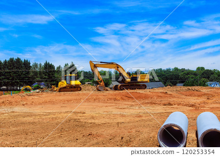 Heavy machinery are actively digging moving earth at construction site clear blue sky enhances vibrant scene of land development. 120253354