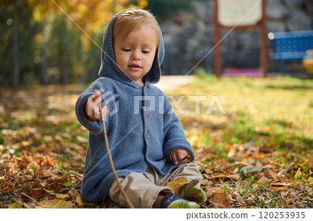 Adorable child playing outdoors in a park during autumn Adorable child playing outdoors in a park during autumn 120253935