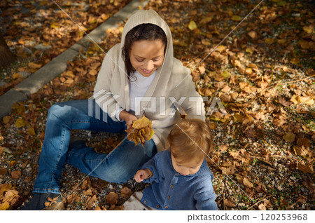 Autumn afternoon with mother and child surrounded by fallen leaves Autumn afternoon with mother and child surrounded by fallen leaves 120253968