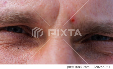 Close up to upset male face looking into camera with a disappointing sight. Upset facial expression of man with blue eyes. Unhappy gaze of despairing young guy. Slow motion 120253984