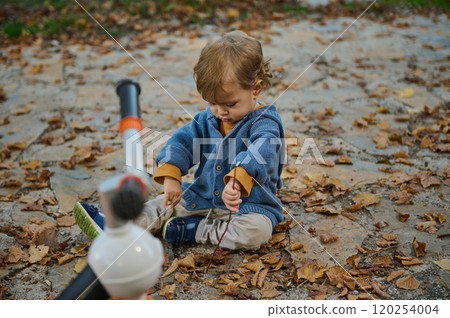 Toddler playing with fallen leaves in autumn outdoors Toddler playing with fallen leaves in autumn outdoors 120254004