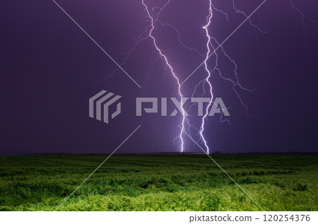 Bright lightnings in dark stormy sky above green field, climate change or weather forecast concept image 120254376