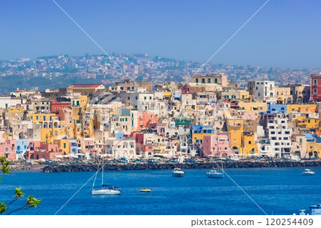 Procida in sunny summer day. Colorful houses, cafes and restaurants, fishing boats and yachts in Marina Corricella, blue sky and azure sea, Procida Island, Italy. Procida in sunny summer day. Colorful houses, cafes and restaurants, fishing boats and yachts in Marina Corricella, blue sky and azure sea, Procida Island, Italy. 120254409