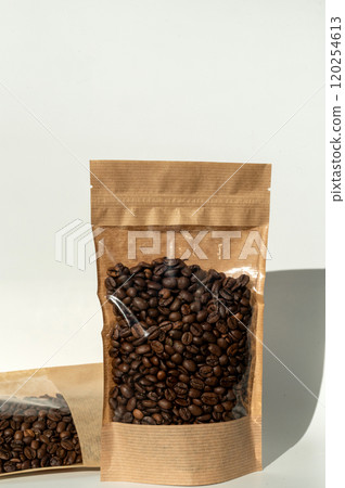 Coffee beans in transparent window pouches on brown paper bags. Coffee beans in transparent window pouches on brown paper bags. 120254613