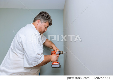 Contractor works diligently on home improvement task, using power drill to install plasterboard wall Contractor works diligently on home improvement task, using power drill to install plasterboard wall 120254644