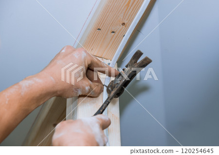 Craftsman carefully using hammer to secure electrical wiring to wooden framing in residential construction project Craftsman carefully using hammer to secure electrical wiring to wooden framing in residential construction project 120254645