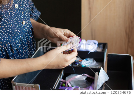Woman Organizing Sewing Supplies at Home Craft Space Woman Organizing Sewing Supplies at Home Craft Space 120254676