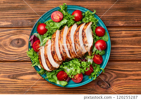 Grilled chicken breast ( fillet ) with lattuce salad and cherry tomatoes . Top view Grilled chicken breast ( fillet ) with lattuce salad and cherry tomatoes . Top view 120255287