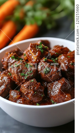 Tender slow cooked beef stew with carrots and herbs served in a white bowl 120255660