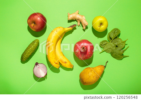 Fresh fruits, vegetables and spices creating a colorful arrangement on green background top view, high contrast with hard light 120256548