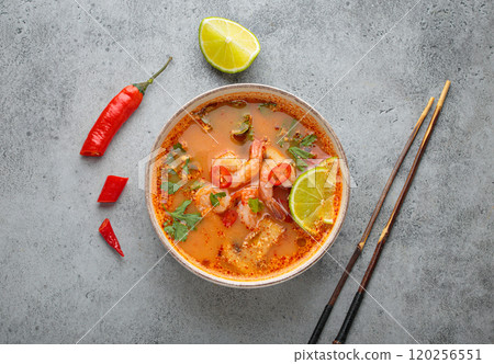 Spicy tom yum soup with shrimps, lime, chili pepper and coriander served in bowl top view, traditional Thai cuisine Spicy tom yum soup with shrimps, lime, chili pepper and coriander served in bowl top view, traditional Thai cuisine 120256551