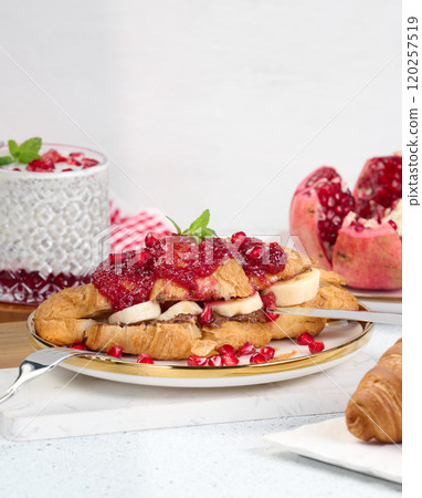 Croissant with chocolate, banana pieces and raspberry jam on a plate Croissant with chocolate, banana pieces and raspberry jam on a plate 120257519