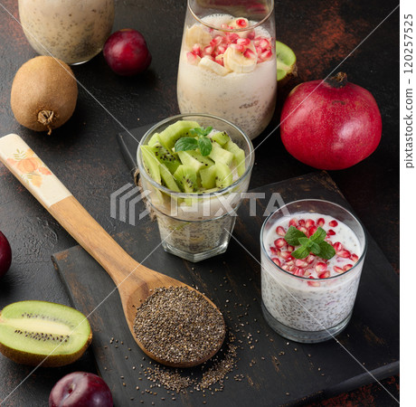 Chia seed glasses filled with yogurt and decorated with fresh fruit pieces on the table, healthy breakfast. 120257525