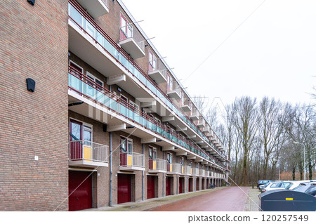 Front view of apartment house with red awnings, Netherlands. Protection against sunlight, rising temperatures and heat waves in summer season 120257549