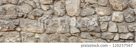 Old coarse pattern panoramic stone wall made of various square natural stones and blocks in beige, ocher and brown 120257567