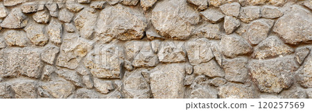 Old coarse pattern panoramic stone wall made of various square natural stones and blocks in beige, ocher and brown 120257569
