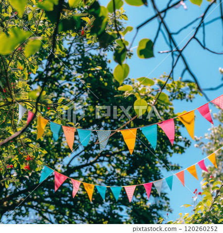 Colorful Bunting Flags Hanging in a Tree Against a Blue Sky Colorful Bunting Flags Hanging in a Tree Against a Blue Sky 120260252