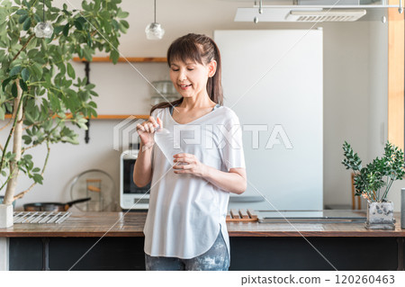 Asian woman hydrating with bottled mineral water after home training Asian woman hydrating with bottled mineral water after home training 120260463