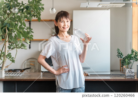 Asian woman hydrating with bottled mineral water after home training 120260466