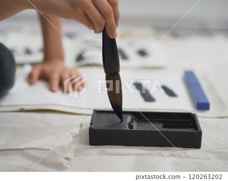 Calligraphy (a child's hand writing kanji with a large brush) 120263202