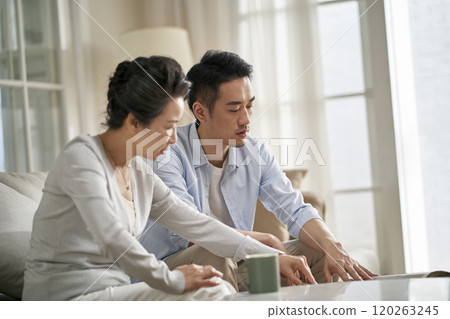 young asian adult son and elderly mother conversing at home 120263245