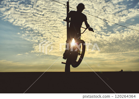 Silhouette unrecognizable Young man doing ramp jump stunt on bmx bicycle on sunset. 120264364