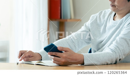 A man thinking while looking at his smartphone A man thinking while looking at his smartphone 120265364