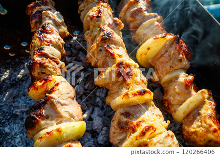 Grilled kebab cooking on metal skewer. Roasted meat cooked at barbecue.Traditional eastern dish, shish kebab. Grill on charcoal and flame, picnic, street food 120266406