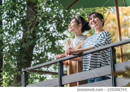Young Asian woman relaxing on the wooden deck of a pension cottage cabin 120266743