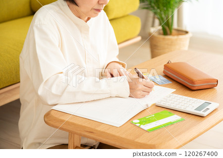 The hands of a middle-aged to senior woman keeping a household account book The hands of a middle-aged to senior woman keeping a household account book 120267400