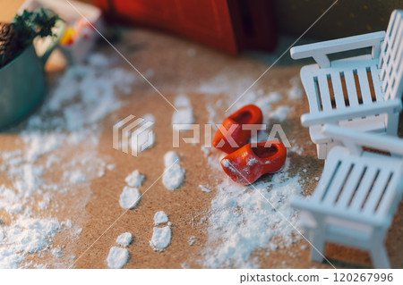 Snowy footprints lead to a miniature winter entrance scene - wooden chairs and warm accessories Snowy footprints lead to a miniature winter entrance scene - wooden chairs and warm accessories 120267996