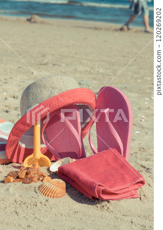 Different accessories for relax on sand. Straw hat, slippers and towel. Summer time on beach 120269202