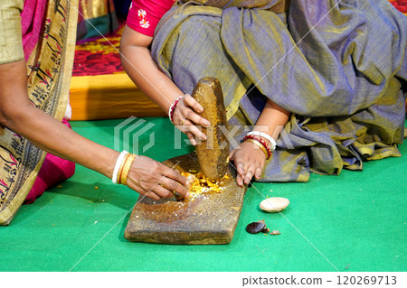 Bengali Woman making turmeric paste in Shil Nora for haldi function 120269713