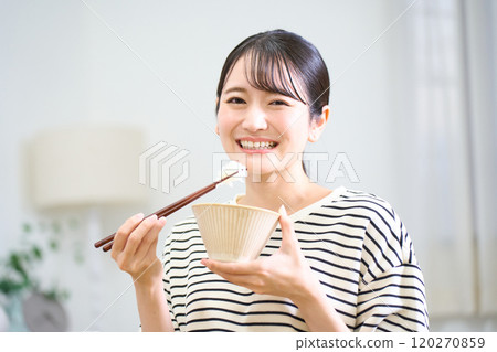 Young woman eating rice 120270859
